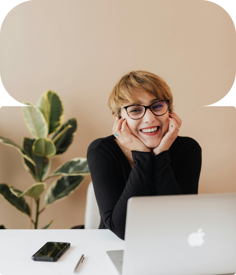 A content design leader smiling at her desk with a laptop and plant